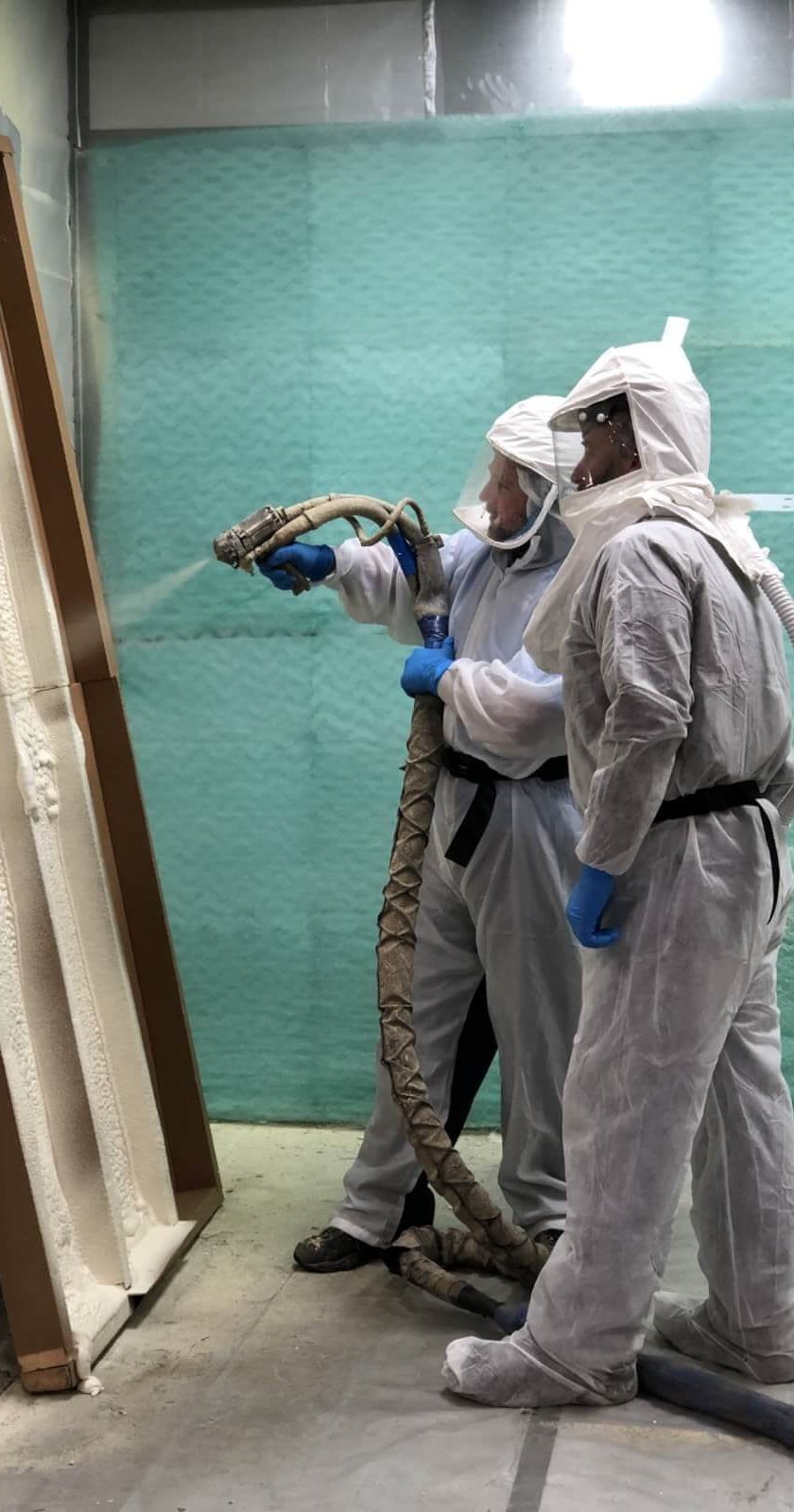 One person using a spray foam gun and another watching.