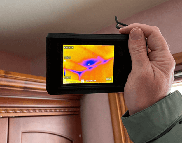 person holding infrared camera to the corner of a house