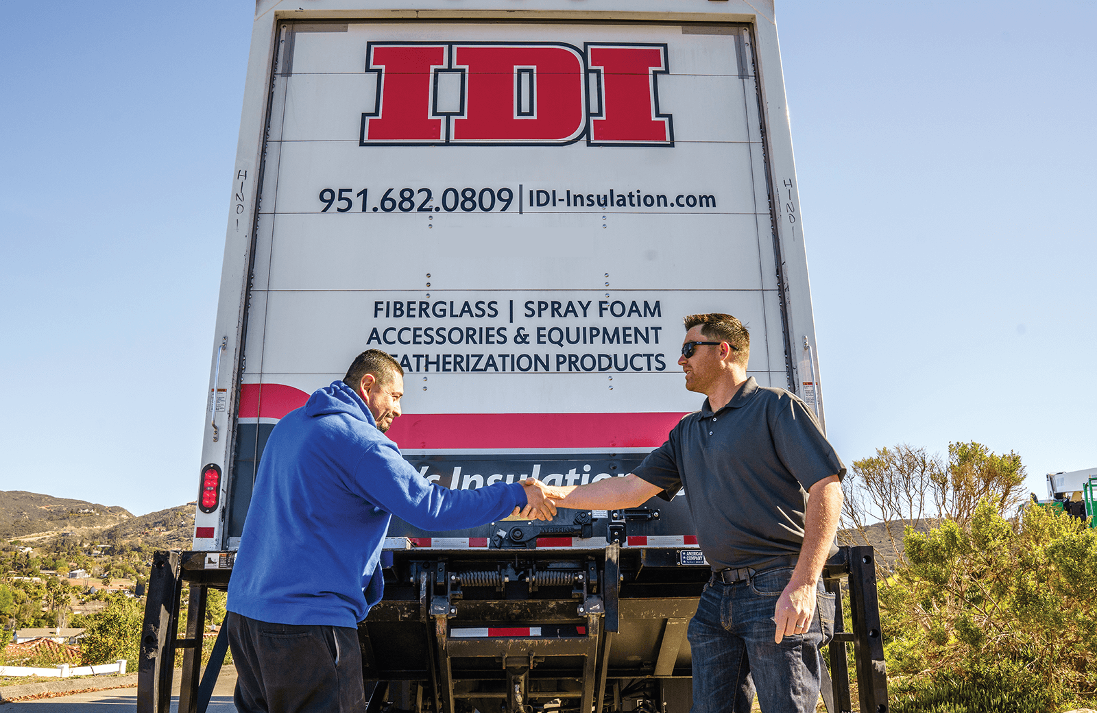 two people shaking hands behind a big rig